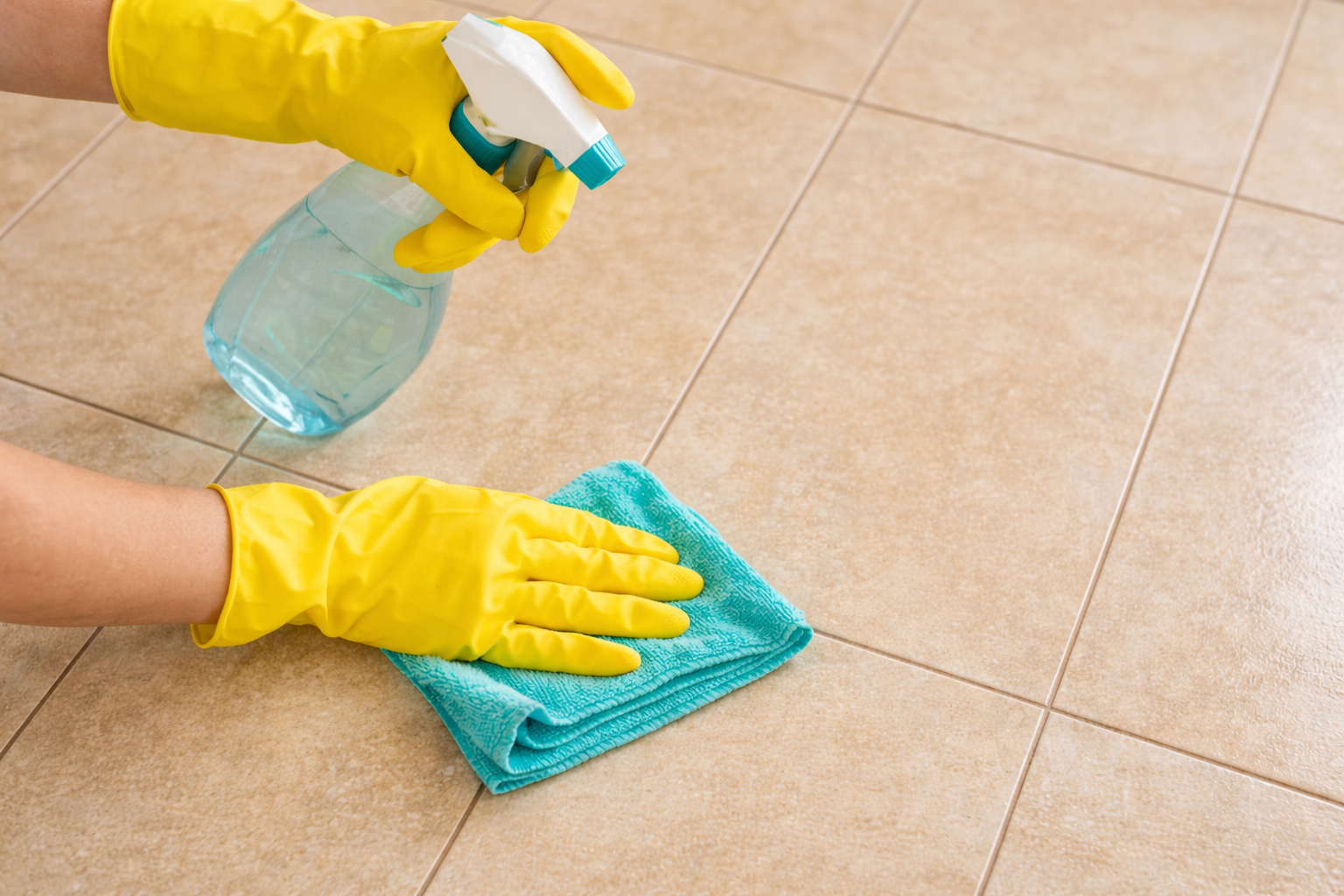 Чистка керамической плитки мягкой губкой и средством для ухода Процесс ухода за керамической плиткой — человек в жёлтых перчатках чистит плитку микрофиброй и спреем